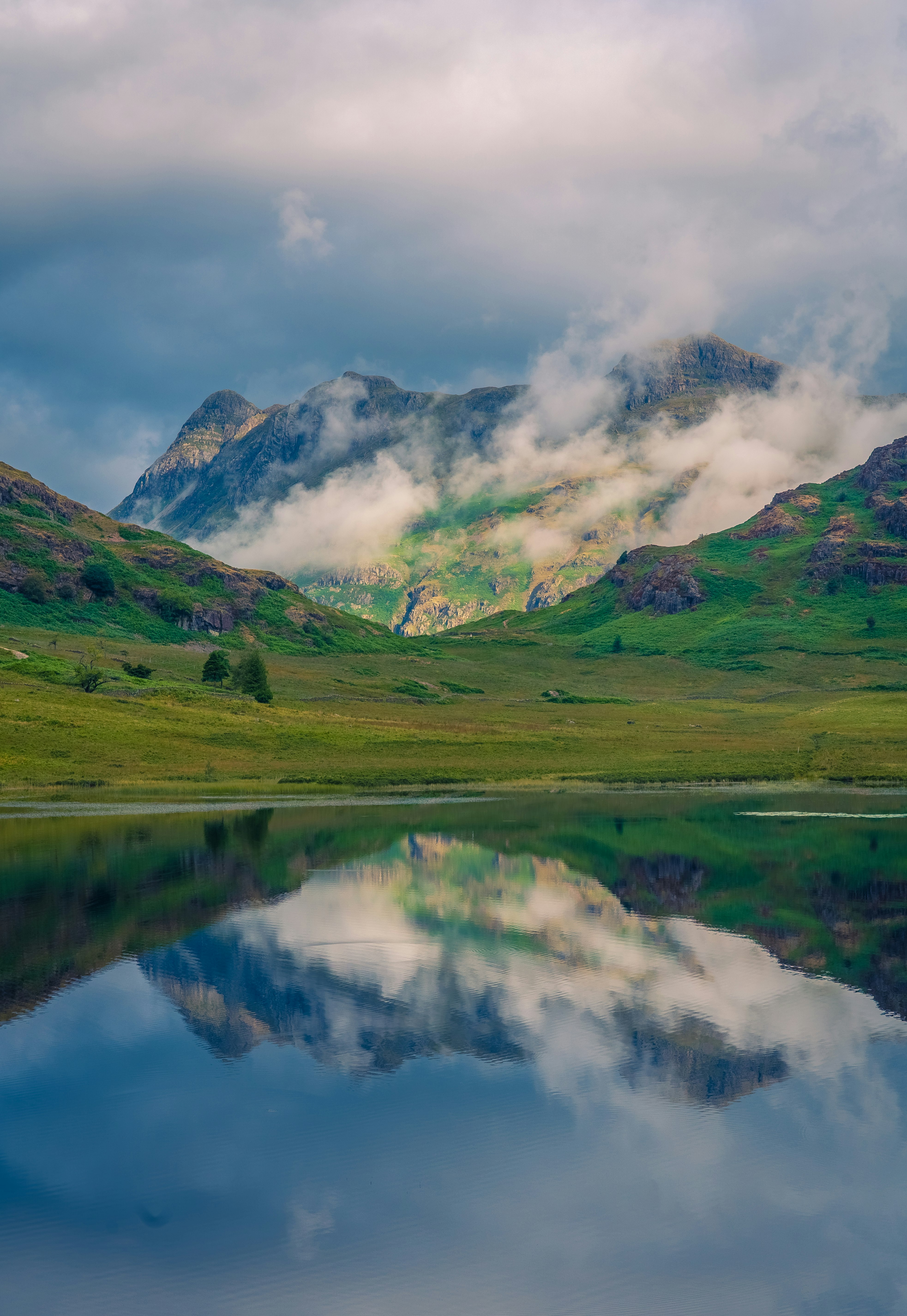 green grass field and mountain ranges near lake